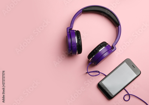 Stylish headphones and modern phone on color background, flat lay. Space for text