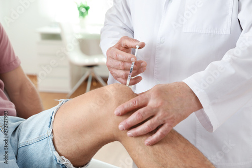 Doctor giving patient injection in clinic, closeup. Knee problem treatment photo