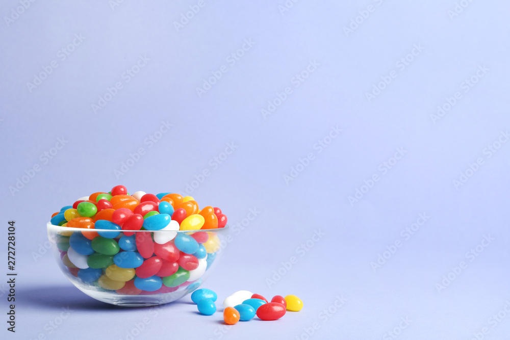 Glass bowl with delicious bright jelly beans on color background Glass bowl with delicious bright jelly beans on color background