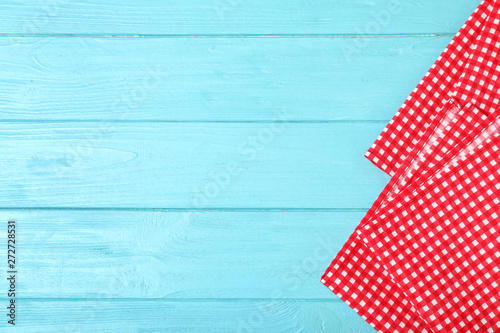 Checkered picnic napkins on color wooden background, top view. Space for text