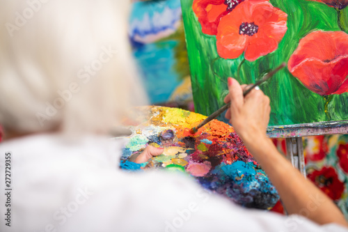 Woman mixing colorful gouache while painting poppies
