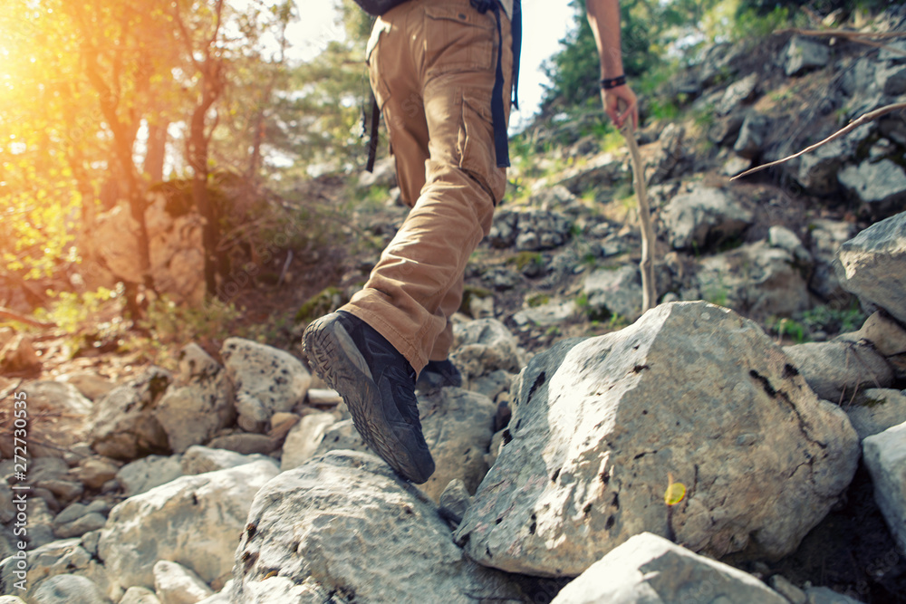 Hiking guy trying to reach at the top of the hill on the rocky path Hiking guy trying to reach at the top of the hill on the rocky path
