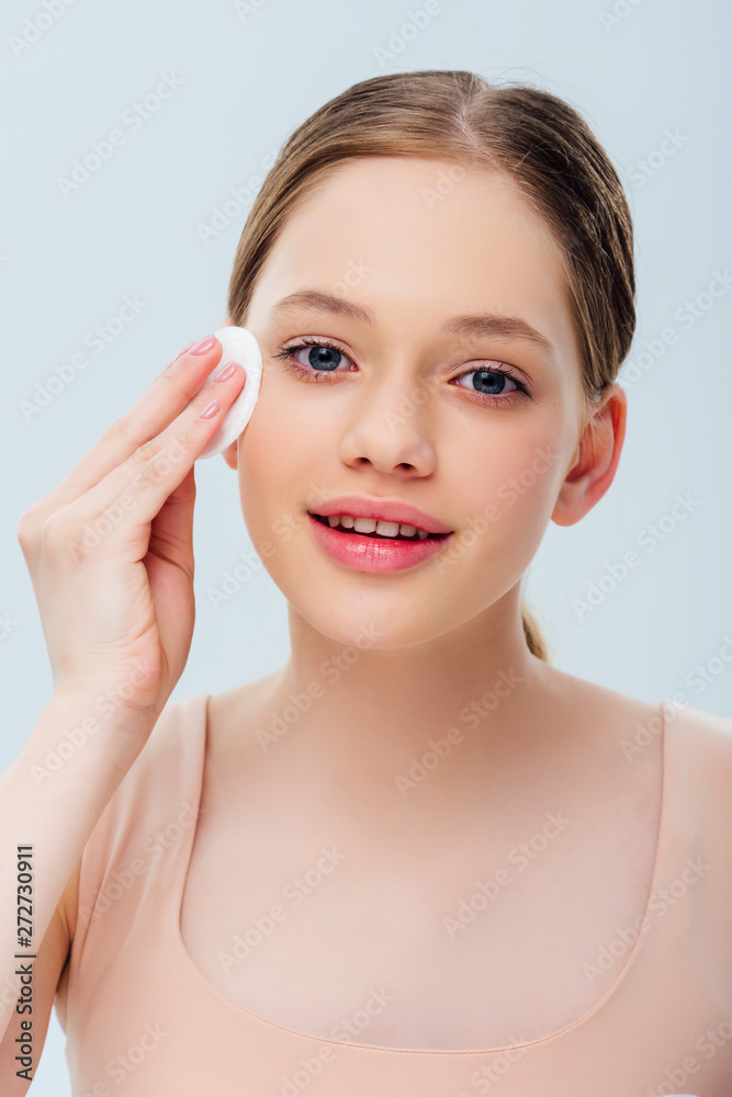 pretty teenage cleansing face with cotton pad isolated on grey