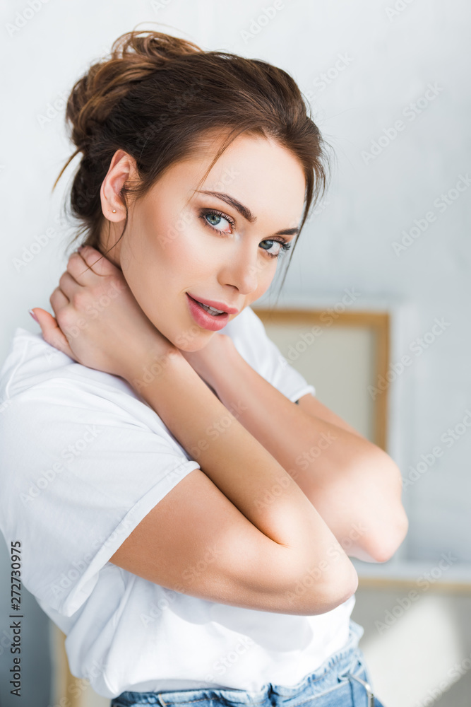 beautiful young woman in white t-shirt looking at camera and touching neck beautiful young woman in white t-shirt looking at camera and touching neck