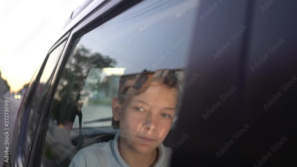 Teenager making phone call while sitting on back seat of a car Teenager making phone call while sitting on back seat of a car