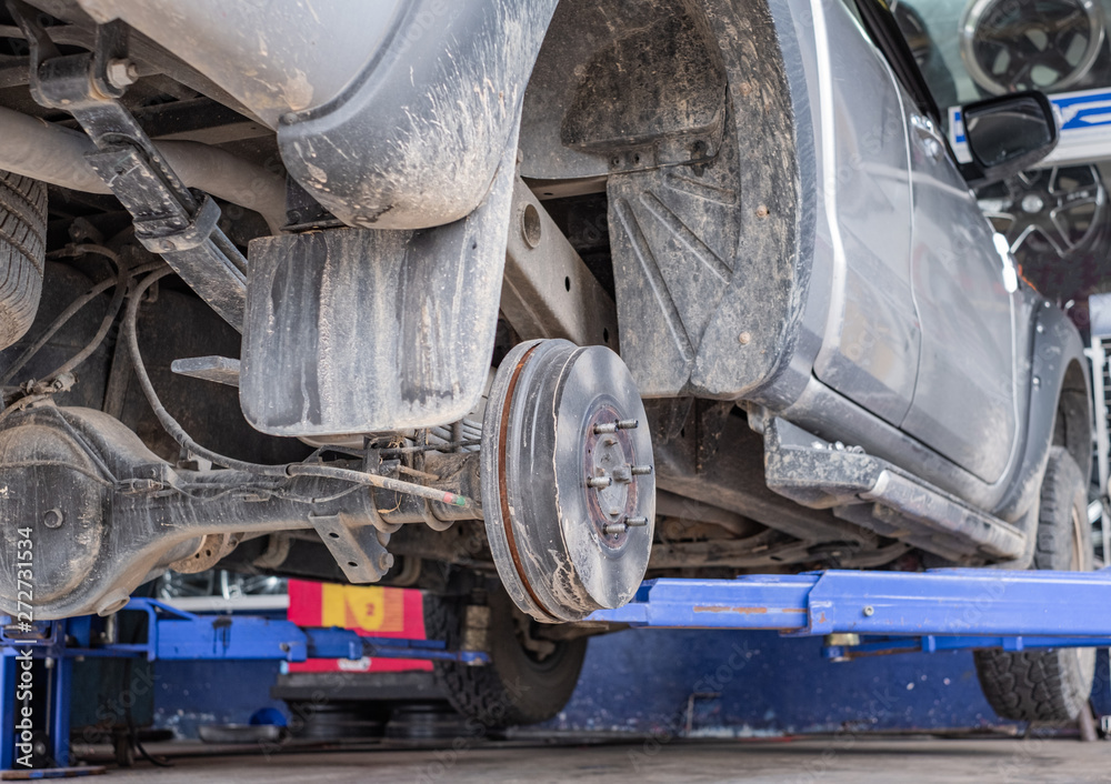 Close up of car disk brake. Car with no wheel on life for repair. Close up of car disk brake. Car with no wheel on life for repair.