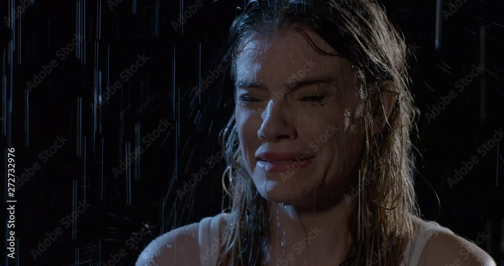 Attractive young woman crying in rain at night. Close up, slow motion 4K recorded at 60fps