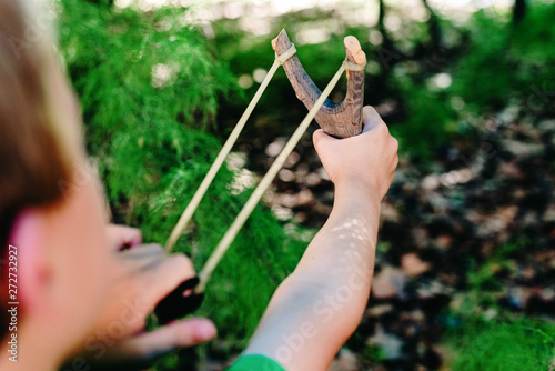 Obraz na płótnie Boy enjoying his summer vacation throwing rocks with a slingshot in a forest