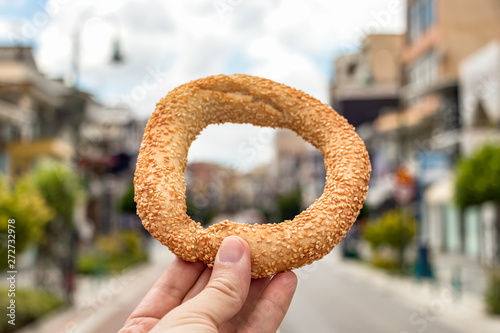 Fototapeta Naklejka Na Ścianę i Meble -  Hand holding a greek koulouri over an urban background in Greece.
