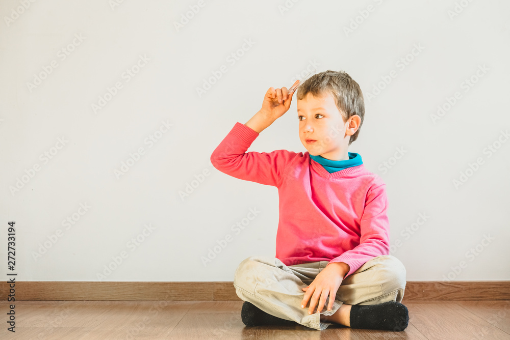 Independent child of 5 years combing himself sitting on the floor of his house - obrazy, fototapety, plakaty 