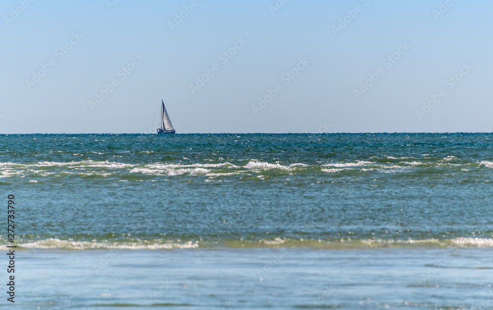 Sailboat in the distance with blue green waters on the Gulf of Mexico