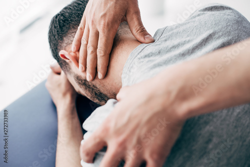 selective focus of chiropractor massaging neck of man in hospital