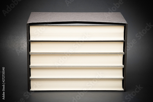 Photography A set of five monochromatic cloth-bound books stored inside a black hard cardboard slipcase set on a slightly graduated and subtly textured dark background