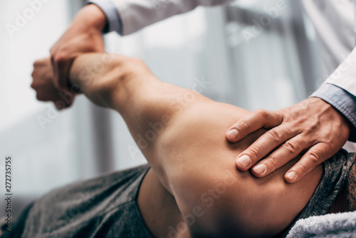 selective focus of chiropractor stretching arm of patient in hospital photo