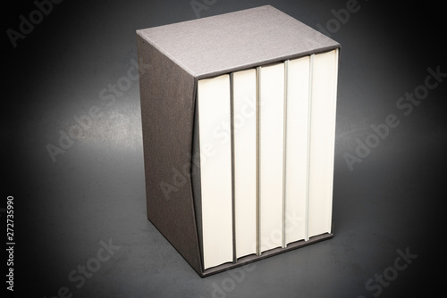 A set of monochromatic cloth-bound books inside an elegant black hard cardboard slipcase and set on a slightly textured and graduated dark background.