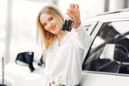 Lady in a car salon. Woman buying the car. Blonde in a white shirt