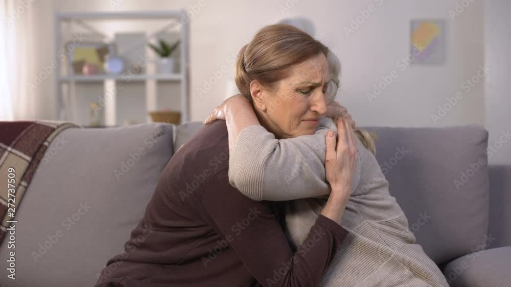 Mature women grieving, hugging and supporting each other, farewell sadness Mature women grieving, hugging and supporting each other, farewell sadness