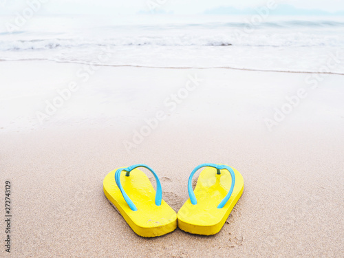 yellow sandal on beige sand summer beach background.