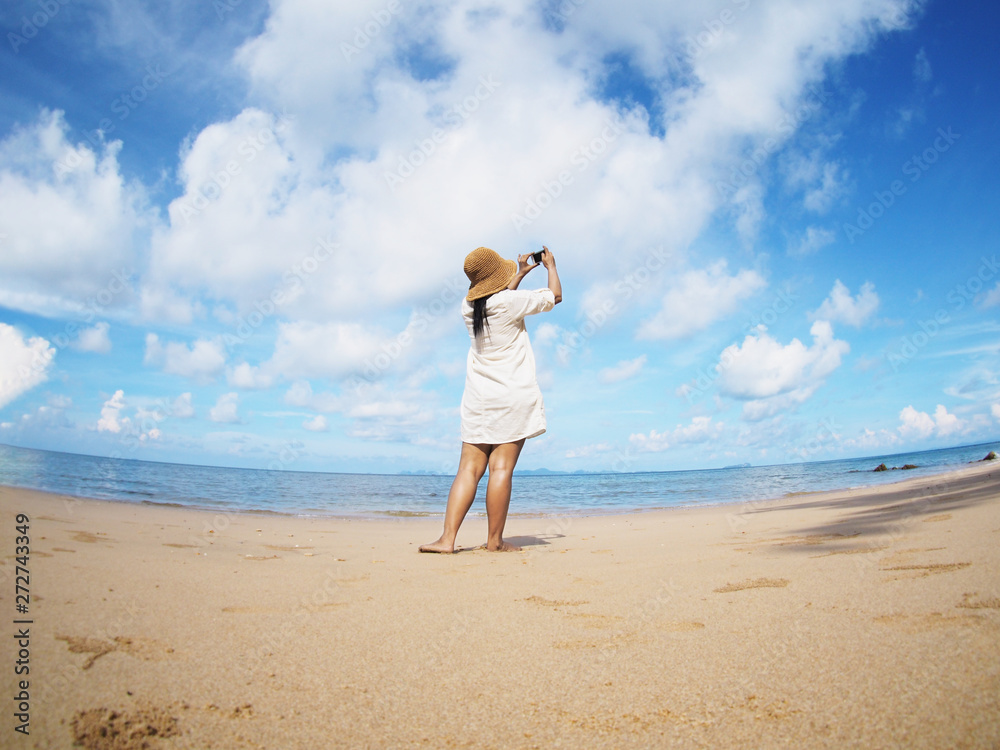 Back view woman taking photograph on the beach., fish eye lens distortion Back view woman taking photograph on the beach., fish eye lens distortion