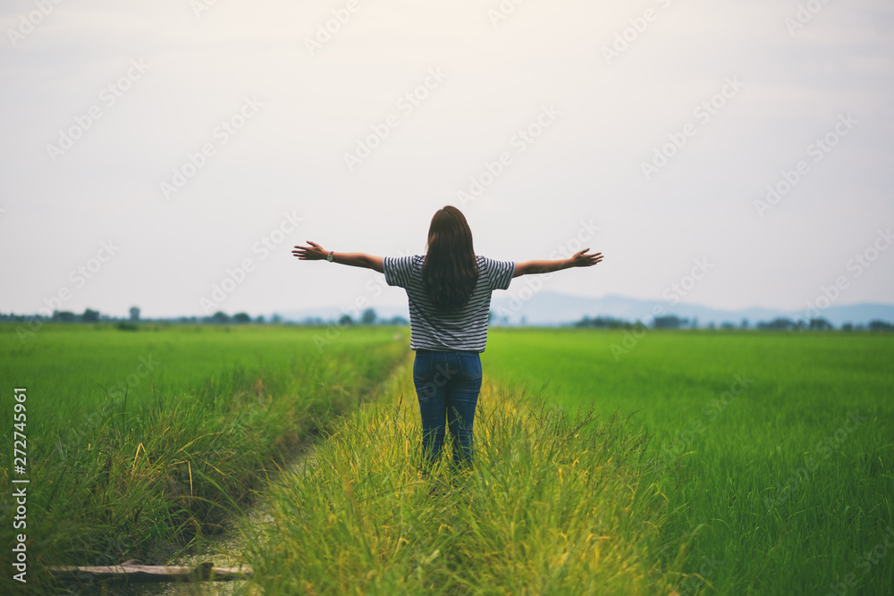 A woman standing and stretching arms in a beautiful rice field with feeling relaxed and fresh A woman standing and stretching arms in a beautiful rice field with feeling relaxed and fresh