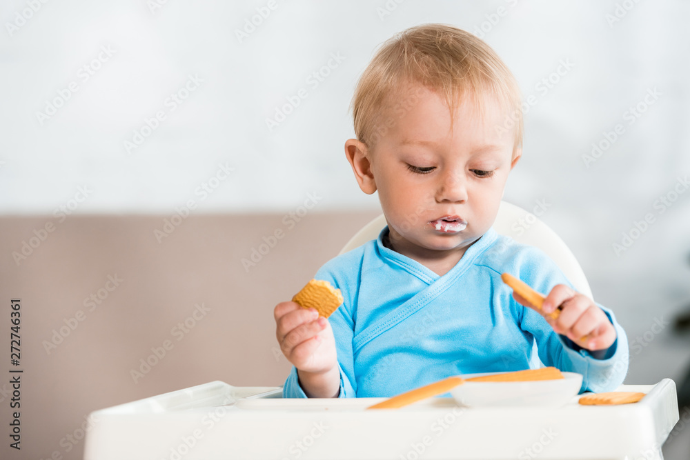 cute toddler kid sitting in feeding chair near sweet cookies at home cute toddler kid sitting in feeding chair near sweet cookies at home