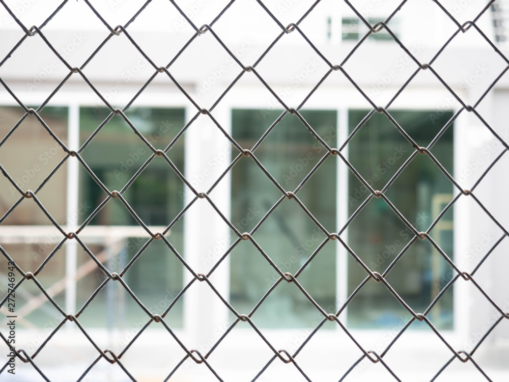 Protected house behind fence,Close up of a wire fence with a blurred Protected house behind fence,Close up of a wire fence with a blurred