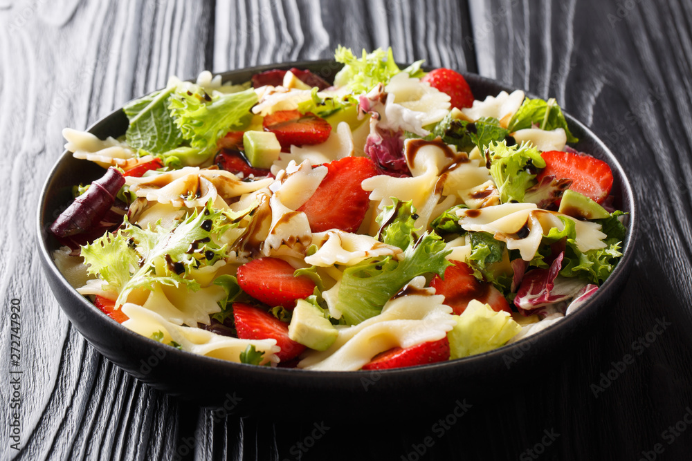 Healthy salad of farfalle pasta with avocado, strawberries, fresh lettuce and balsamic sauce close-up on a plate. horizontal Healthy salad of farfalle pasta with avocado, strawberries, fresh lettuce and balsamic sauce close-up on a plate. horizontal