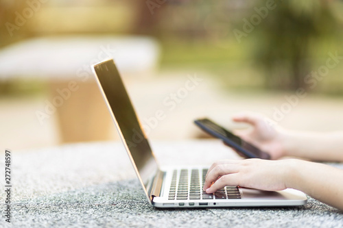Close-up of business female working with laptop and smartphone in at the park on office outdoor.