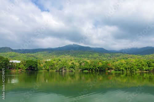 green tree with mountain and reservoir blue sky background with white clouds