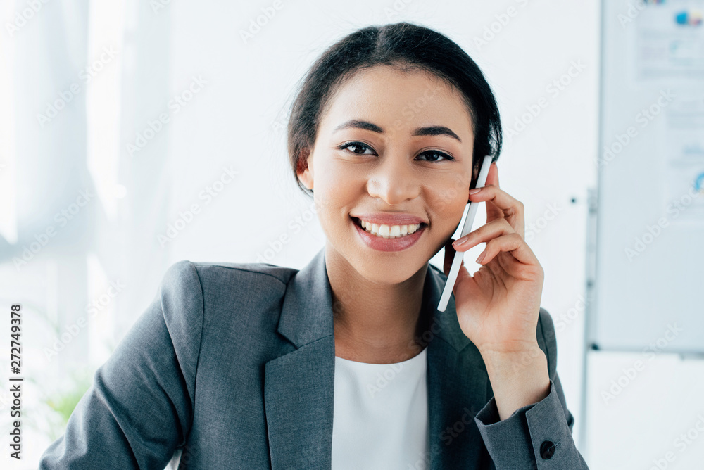 beautiful latin businesswoman smiling at camera while talking on smartphone in office beautiful latin businesswoman smiling at camera while talking on smartphone in office
