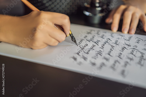 Calligrapher hands writes phrase on white paper. Bible phrase about love Inscribing ornamental decorated letters. Calligraphy, graphic design, lettering, handwriting, creation concept