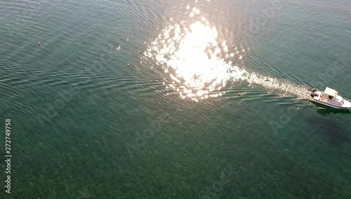 Drone view of a small boat passing by with sun reflection on the water from the beautiful Greek island trizonia. photo