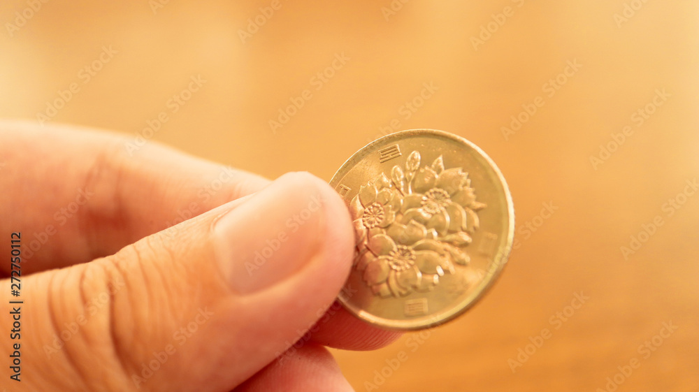 Fototapeta premium Close up the 100 Japanese Yen Coin on Finger