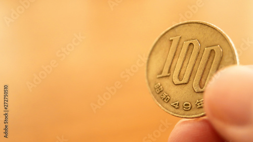 Close up the 100 Japanese Yen Coin on Finger