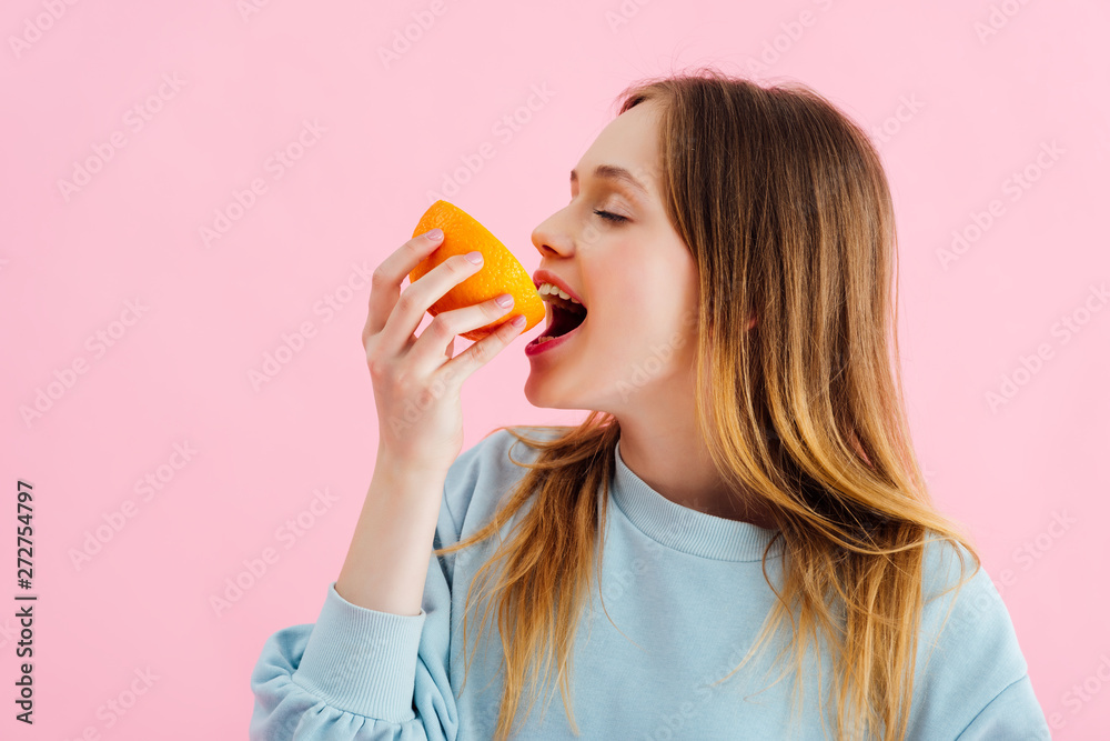 pretty teenage girl with closed eyes biting orange half isolated on pink pretty teenage girl with closed eyes biting orange half isolated on pink