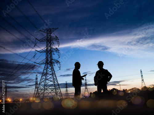 Silhouette Successful male engineer standing survey work on construction over blurred high-voltage pylons and construction. examination, inspection, survey