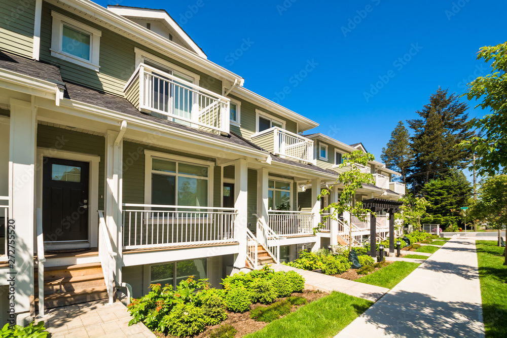 Brand new townhouses with concrete pavement in front. Front side of townhouses on sunny day in Canada.