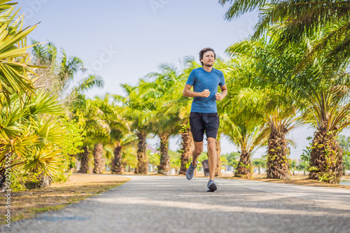 Runner athlete running at tropical park. man fitness sunrise jogging workout wellness concept