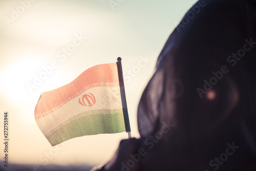 Muslim woman in scarf with Iranian flag at sunset.Concept photo