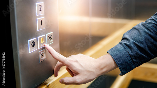 Male forefinger pressing on emergency stop and alarm button in elevator (lift). Mechanical engineering concept