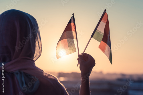 Muslim woman in scarf with Iranian and Germany flags of at sunset.Concept photo