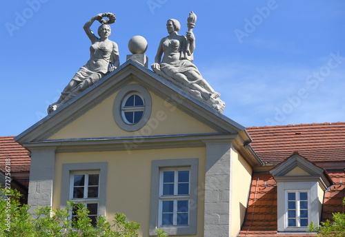 Skulpturen auf dem Dreiecksgiebel eines Gebäudes am Anger vor strahlend blauem Himmel photo