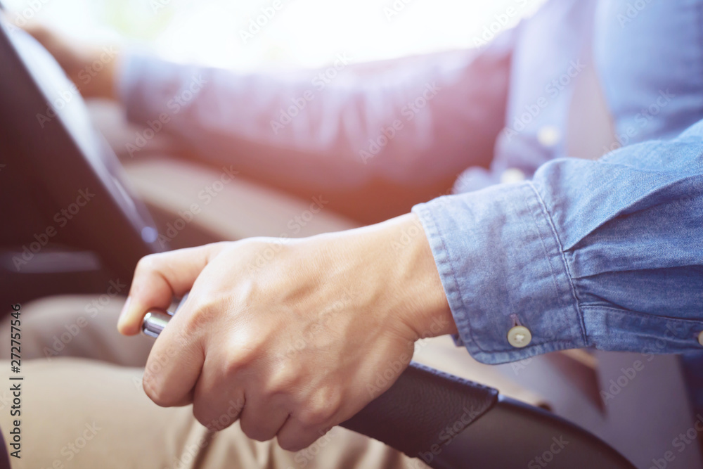 Obraz premium Closeup of person hand pulling handbrake lever in car For safety while parking.