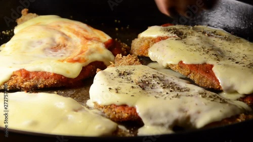 Milanesa Napolitana being prepared with oregano, traditional Argentina meal