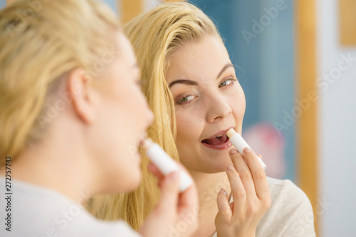 Woman in bathroom applying lip balm