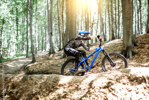Professional cyclist riding downhill on the mtb bicycle on the forest track. Concept of an extreme sport and enduro cycling