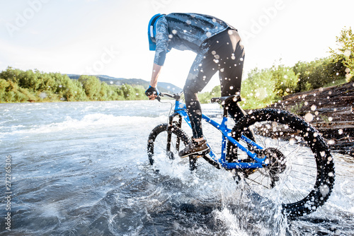 Canvastavla Professional well-equipped cyclist riding on the rocky riverside in the mountains