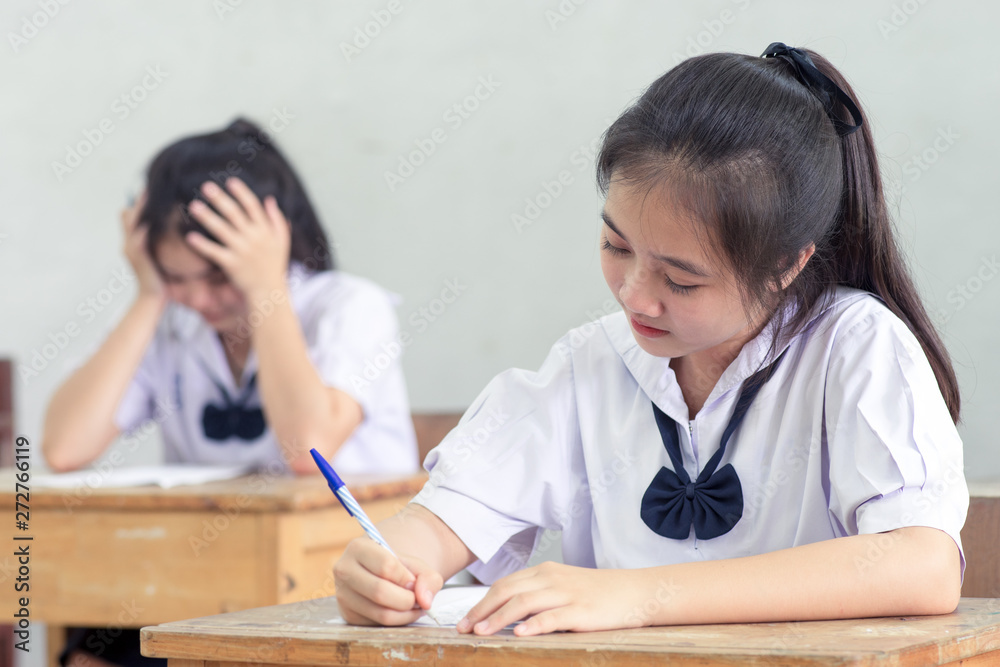 Asian girl student reading and writing exam with stress.