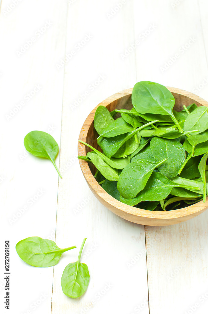 Fresh green spinach leaves on wooden bowl on white wooden rustic background top view copy space. Baby young spinach leaves, Ingredient for salad, healthy food, diet. Nutrition concept. Fresh green spinach leaves on wooden bowl on white wooden rustic background top view copy space. Baby young spinach leaves, Ingredient for salad, healthy food, diet. Nutrition concept.