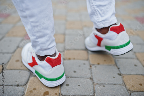 Close up sneakers in african man at white pants.